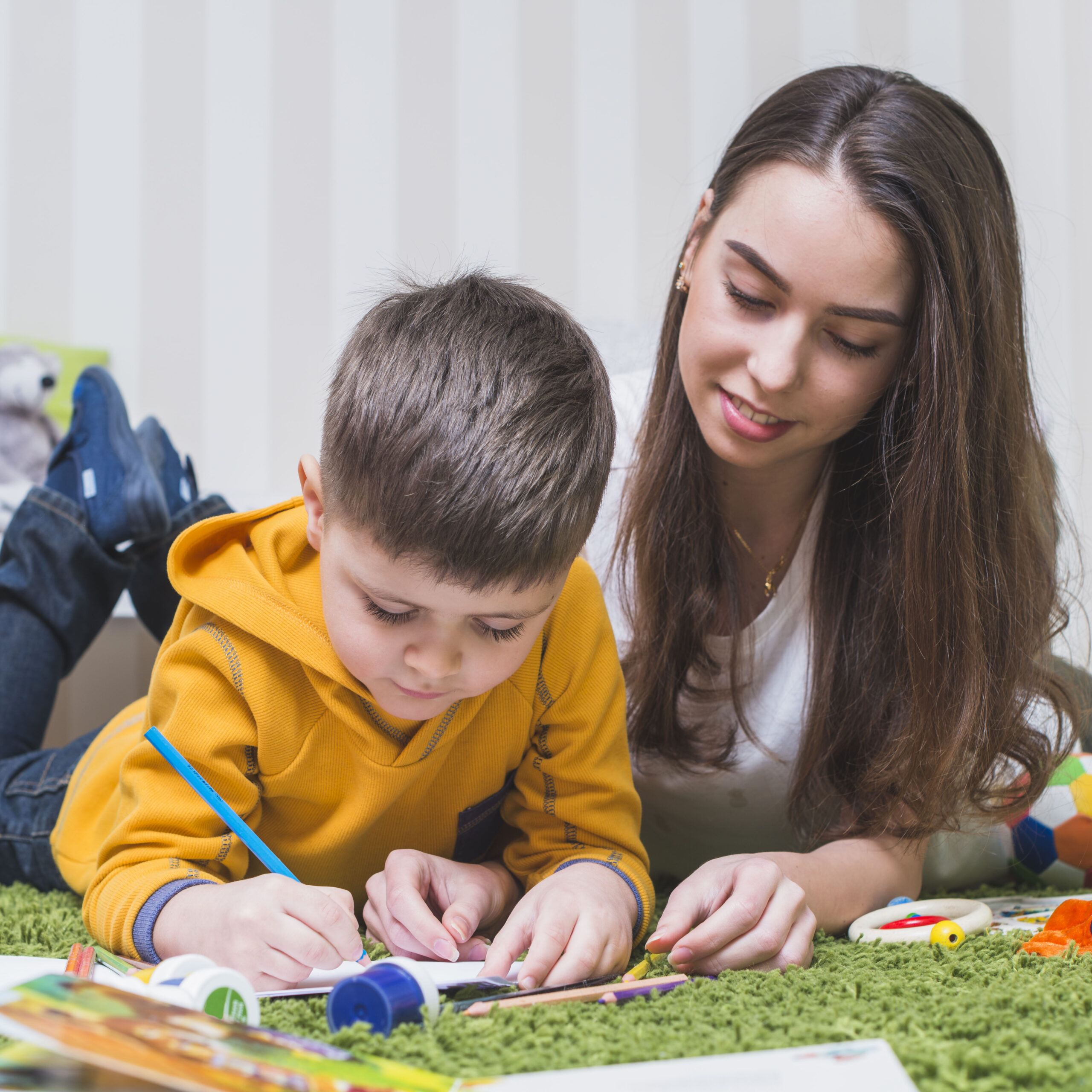 Therapist guiding a young boy with a drawing activity